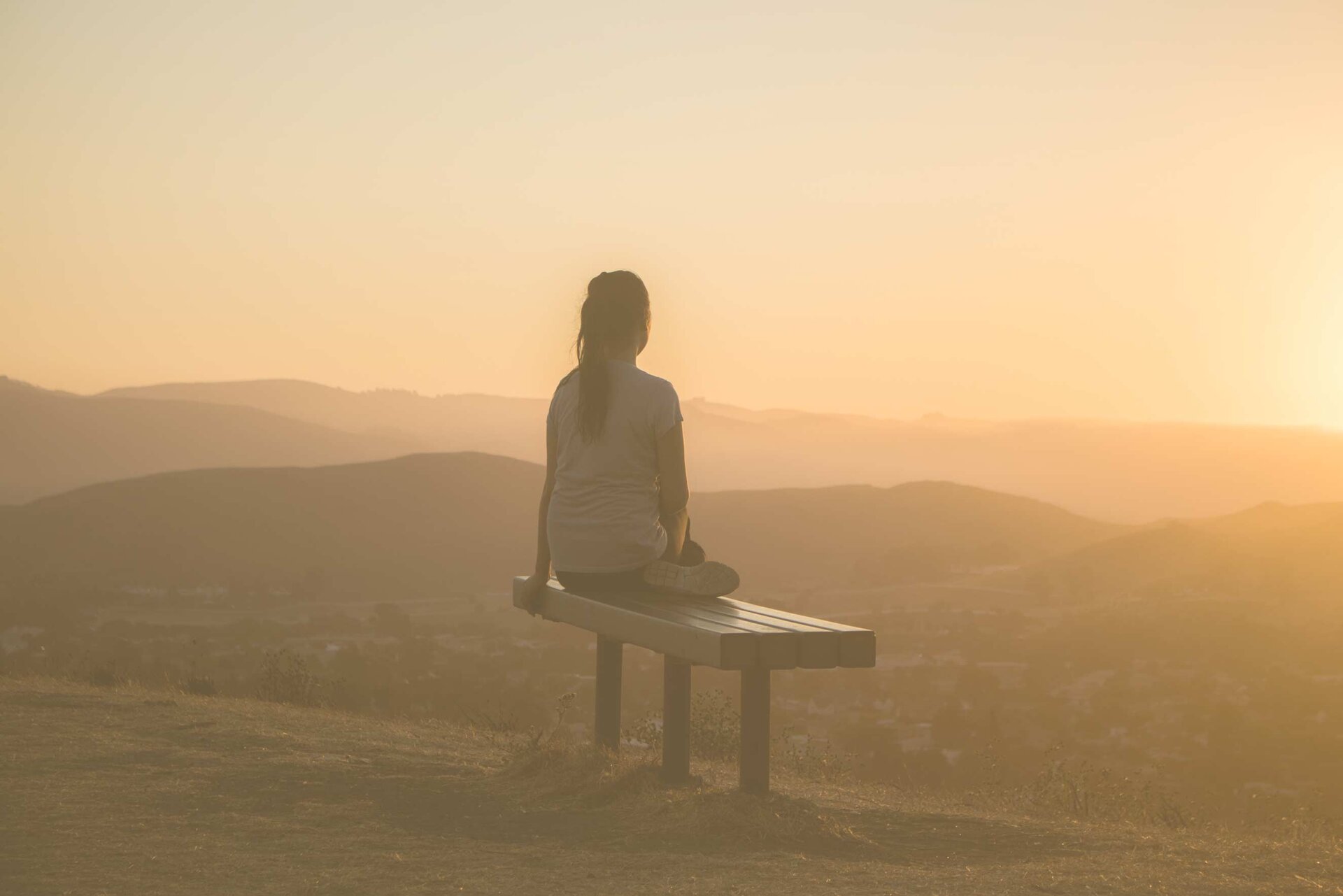 woman sitting on a bench watching the sunset